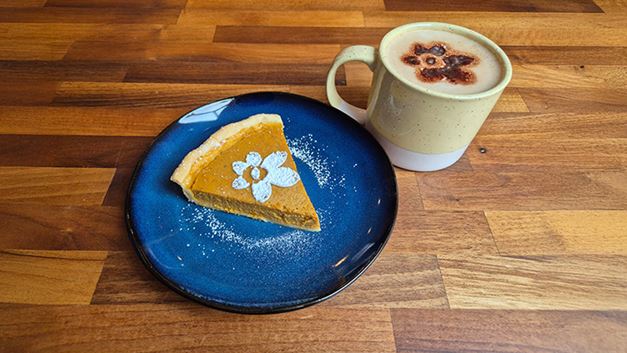 A pie with a Marie Curie cake stencil on it and a cup of tea