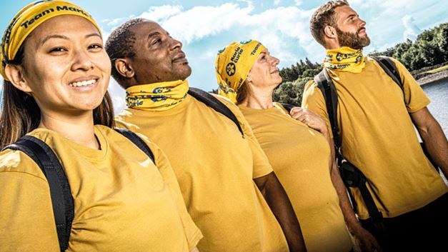 Group of trekkers are wearing yellow t-shirts and looking out at the scenery